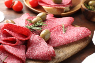 Ahşap masada servis edilen zeytinli ve biberiyeli lezzetli sosisler.