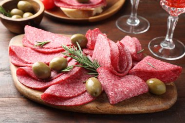 Ahşap masada servis edilen zeytinli ve biberiyeli lezzetli sosisler.