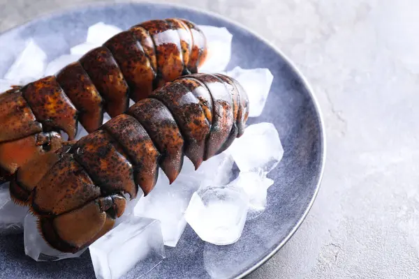 Çiğ ıstakoz kuyruğu, gri masada buzlu, yakın plan.