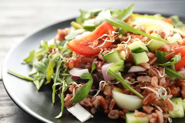 Siyah ahşap masada kahverengi pirinçli leziz salata, yakın plan.