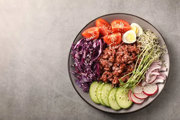 Gri masada kahverengi pirinçli lezzetli salata, üst manzara. Metin için boşluk