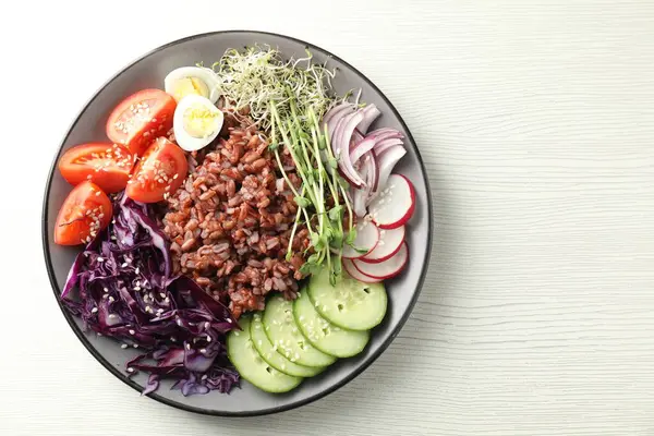 Beyaz ahşap masada kahverengi pirinçli lezzetli bir salata.