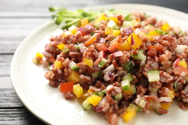 Siyah ahşap masada kahverengi pirinçli lezzetli salata, yakın plan.