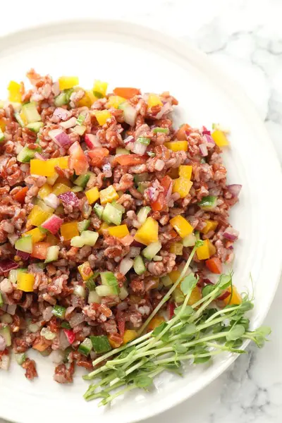 Beyaz mermer masada kahverengi pirinçli lezzetli bir salata.