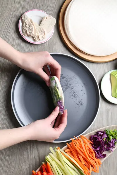 Gri ahşap masada nefis börek yapan bir kadın.