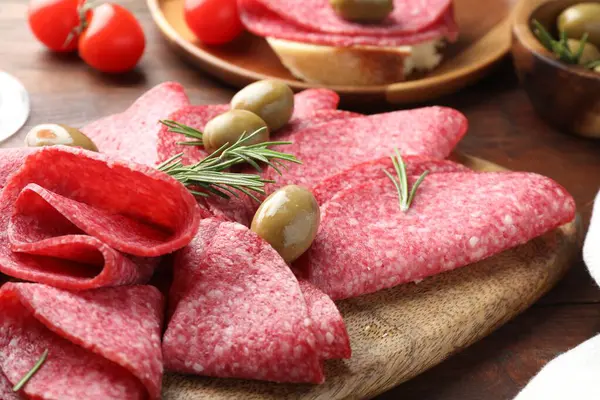 Ahşap masada servis edilen zeytinli ve biberiyeli lezzetli sosisler.