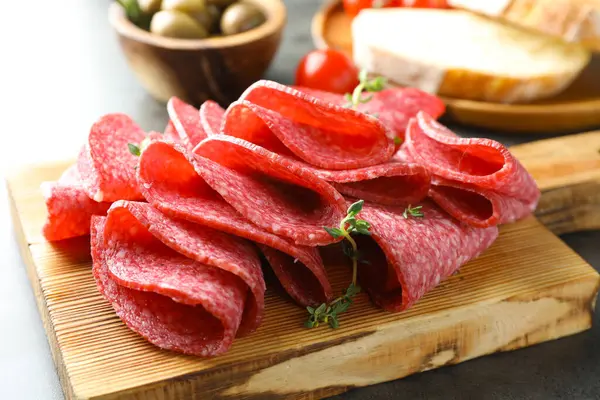 Gri masada servis edilen lezzetli sosis dilimleri, yakın plan.