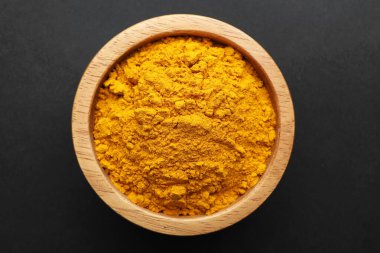 Siyah arka plandaki kasede zerdeçal tozu, üst manzara. Aromatik baharat