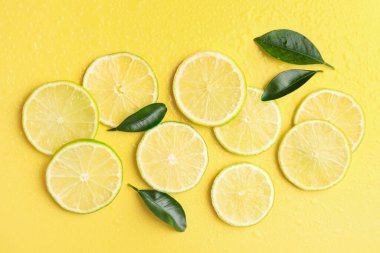 Taze limon dilimleri ve sarı arka planda yeşil yapraklar.