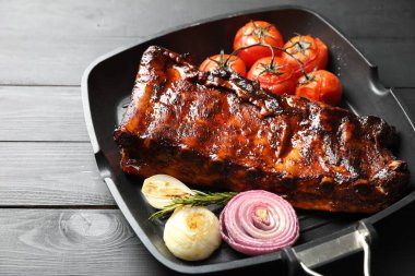 Biberiyeli domuz pirzolası, domates ve soğan. Gri ahşap masada, yakın plan.