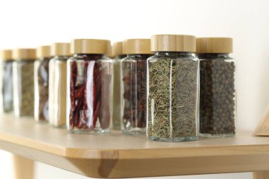 Kapalı alanda, ahşap masadaki kavanozlardaki farklı aromatik baharatlar.