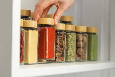 Kapalı mekanda kırmızı biber tozlu kavanoz alan kadın, yakın plan.