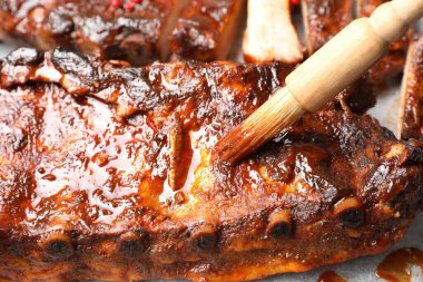 Lezzetli pirzolaların üzerine fırçayla sos serpiştiriyorum.