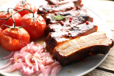Lezzetli domuz pirzolası, kurutulmuş domates ve ahşap masada soğan, yakın plan.