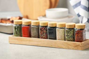 Işık masasındaki kavanozlarda farklı aromatik baharatlar, yakın plan.