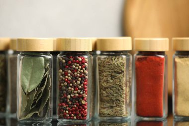 Ayna yüzeyindeki kavanozlarda farklı aromatik baharatlar, yakın plan.