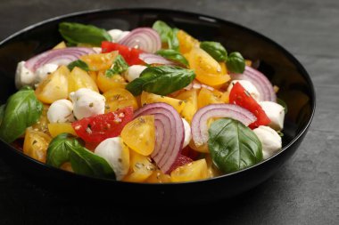 Sarı domatesli lezzetli salata, fesleğen, soğan ve siyah masada mozzarella peyniri, yakın plan.