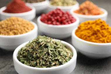 Gri masada farklı aromatik baharatlar, yakın plan.