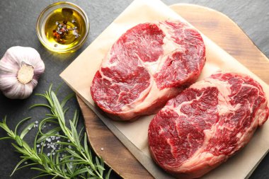 Çiğ et parçaları ve baharatlar siyah masanın üzerinde, düz yatıyordu.