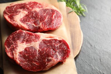 Siyah masada çiğ et ve biberiye parçaları, yakın plan. Metin için boşluk