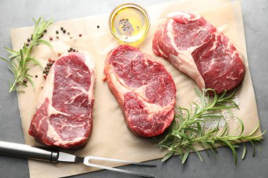 Çiğ et, baharat ve çatal parçaları gri masada, düz yatıyordu.