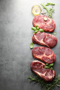 Çiğ et ve baharat parçaları gri masada, düz yerde. Metin için boşluk