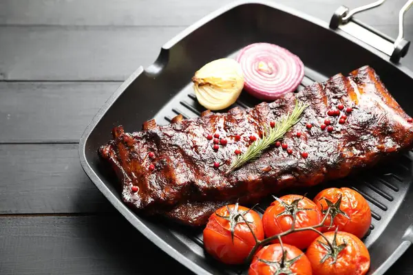 Biberiyeli domuz pirzolası, domates ve soğan. Gri ahşap masada, yakın plan.