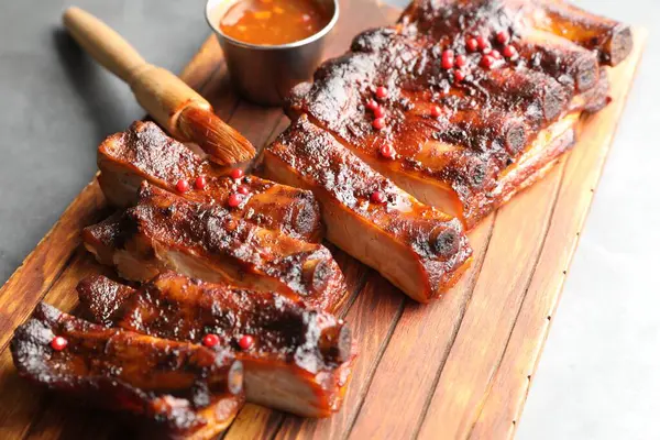 Lezzetli kaburgalar, sos ve fırça gri masada, yakın plan.