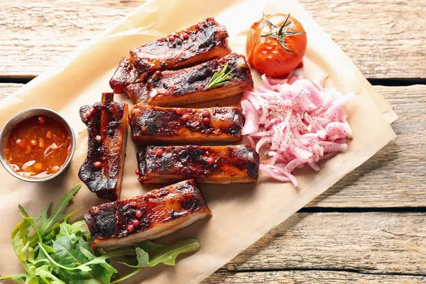 Lezzetli domuz pirzolası, sos, roka ve soğan ahşap masa, üst manzara.