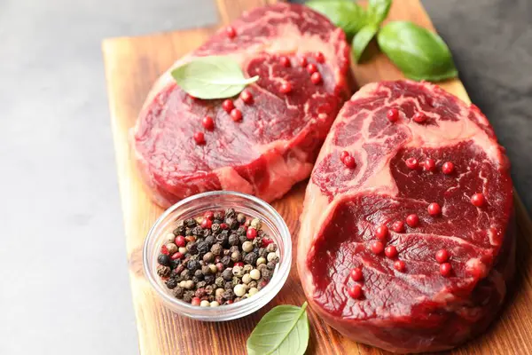 Gri masada çiğ et ve baharat parçaları, yakın plan.