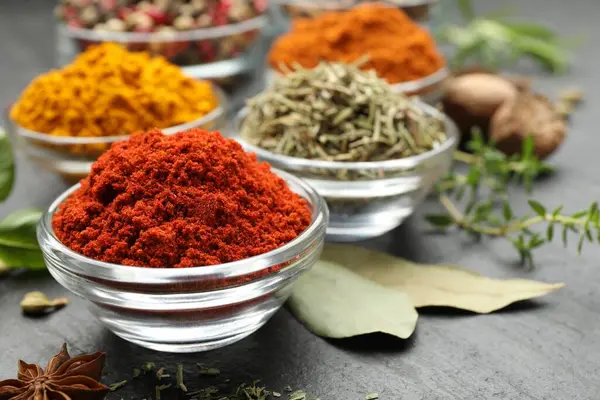 Gri masada farklı aromatik baharatlar, yakın plan.