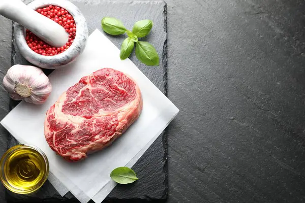 Bir parça çiğ et ve baharat siyah masada, düz yerde. Metin için boşluk