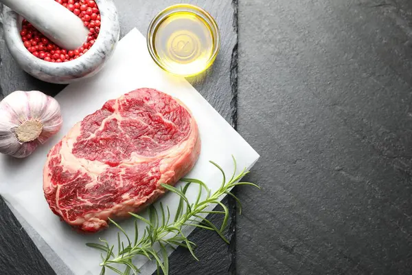 Bir parça çiğ et ve baharat siyah masada, düz yerde. Metin için boşluk
