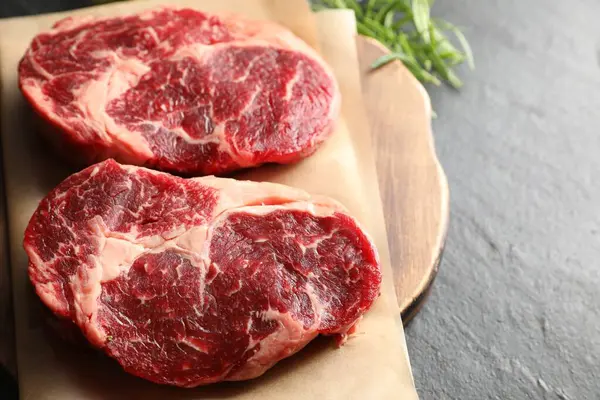 Siyah masada çiğ et ve biberiye parçaları, yakın plan. Metin için boşluk