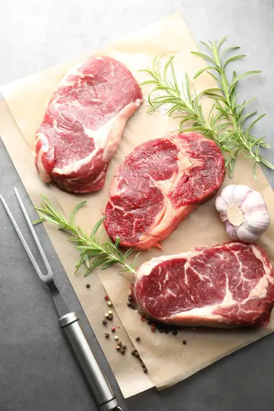 Çiğ et, baharat ve çatal parçaları gri masada, düz yatıyordu.