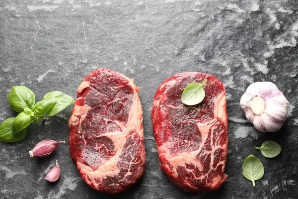 Koyu masa üzerinde çiğ et ve baharat parçaları, düz. Metin için boşluk