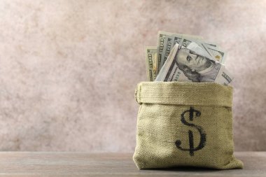 Tahta masanın üzerinde bir sürü dolar banknot olan çanta, metin için yer.