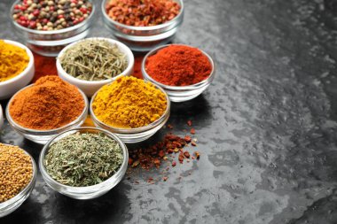 Karanlık masadaki kaselerde farklı aromatik baharatlar, yakın plan. Metin için boşluk