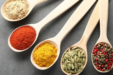 Gri masadaki kaşıklardaki farklı baharatlar düzdü.