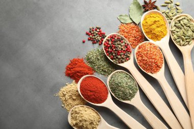 Gri masadaki kaşıklarda bir sürü farklı baharat var. Metin için boşluk