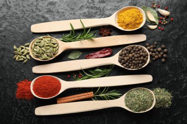 Siyah masadaki kaşıklarda bir sürü farklı baharat var.