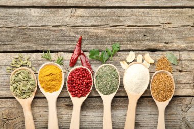 Tahta masadaki kaşıklardaki farklı aromatik baharatlar. Metin için boşluk