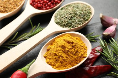 Siyah masada kaşıklardaki farklı aromatik baharatlar, yakın plan.