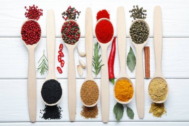 Beyaz ahşap masadaki kaşıklardaki farklı aromatik baharatlar.