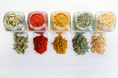 Beyaz masadaki kavanozlarda farklı aromatik baharatlar var.