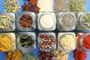 Mavi arka planda kavanozlarda farklı aromatik baharatlar var.