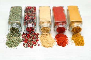 Beyaz masadaki kavanozlarda farklı aromatik baharatlar