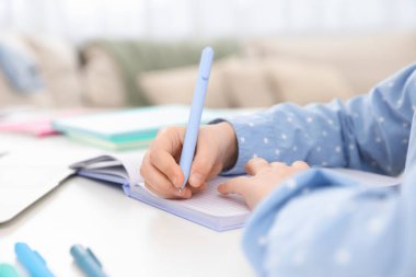 Küçük kız ev ödevlerini içeride yapıyor, yakın plan.