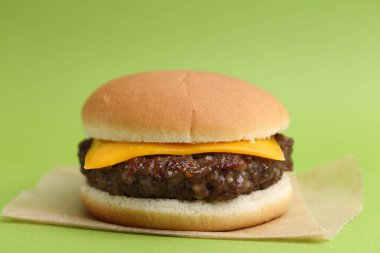 Yeşil arka planda lezzetli köfteli çizburger, yakın plan.