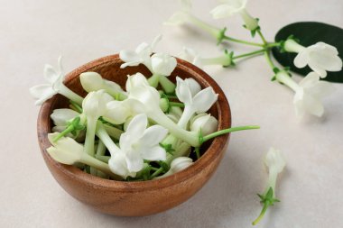 Bej masanın üzerinde yasemin çiçekleri olan kase, yakın plan.